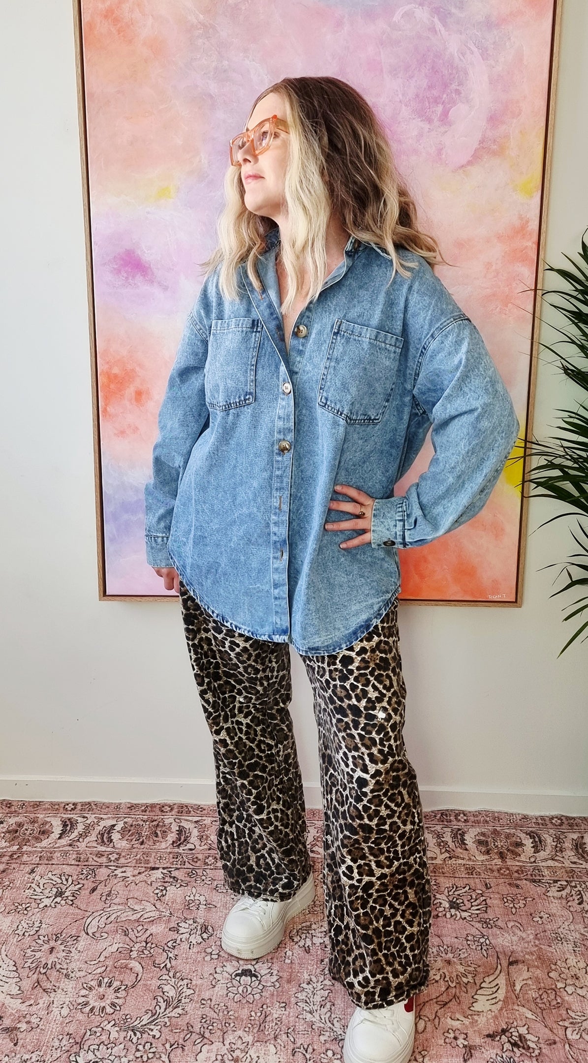 Front view of a light denim oversized shacket with white Western-style illustrations including a snake, flames, dice, and "By Frankie" banner text on the back. Tegan wears the medium and is a size 10 to 12. 