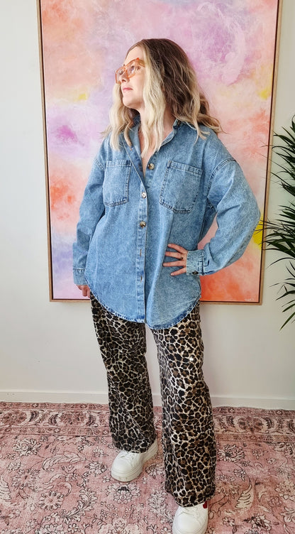 Front view of a light denim oversized shacket with white Western-style illustrations including a snake, flames, dice, and "By Frankie" banner text on the back. Tegan wears the medium and is a size 10 to 12. 
