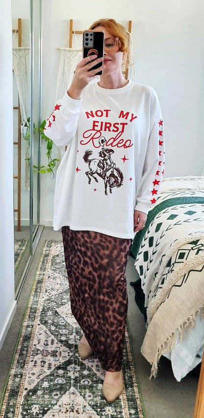 Tegan wearing the Not My First Rodeo Set by By Frankie in size Medium. Features a white oversized sweatshirt with red rodeo graphic and star-print sleeves, paired with a brown leopard-print mesh skirt. Tegan is AU size 10.